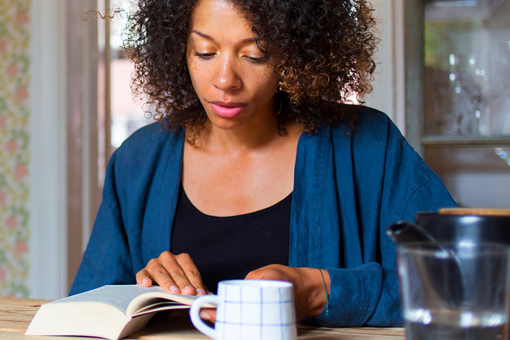 Left-handed woman writing diary, close up of hands with pencil and notebook